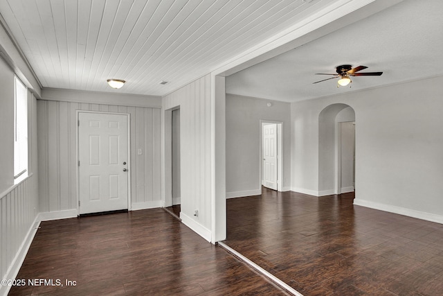 entryway featuring arched walkways, wood finished floors, a ceiling fan, and baseboards