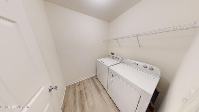 washroom featuring laundry area, baseboards, light wood-style floors, and washing machine and clothes dryer