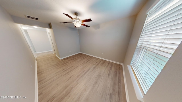 empty room featuring light wood-type flooring, visible vents, ceiling fan, and baseboards