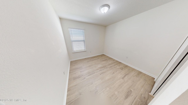 empty room with light wood-style flooring and baseboards