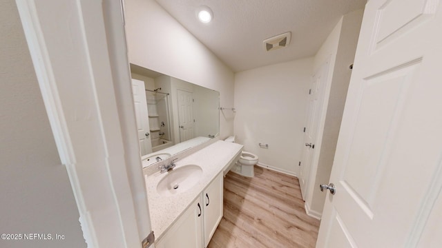 full bath with visible vents, toilet, vanity, wood finished floors, and shower / bathtub combination