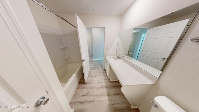 full bathroom featuring visible vents, toilet, wood finished floors, vanity, and shower / washtub combination