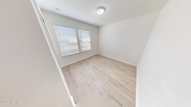 spare room with baseboards and wood finished floors