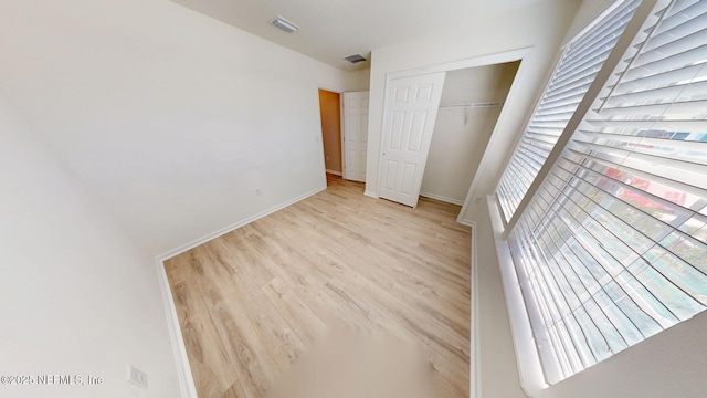 unfurnished bedroom featuring light wood finished floors, a closet, visible vents, and baseboards