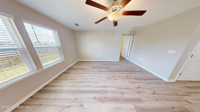 empty room featuring a ceiling fan, visible vents, light wood-style flooring, and baseboards