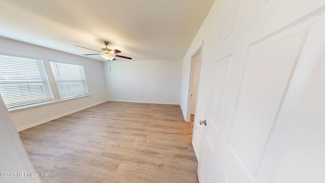 unfurnished room featuring light wood-type flooring, ceiling fan, and baseboards