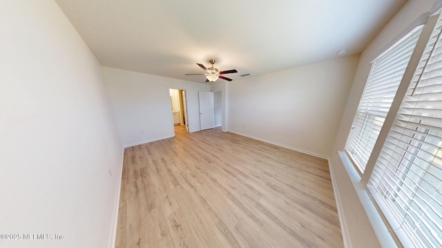 empty room with ceiling fan, light wood-type flooring, visible vents, and baseboards