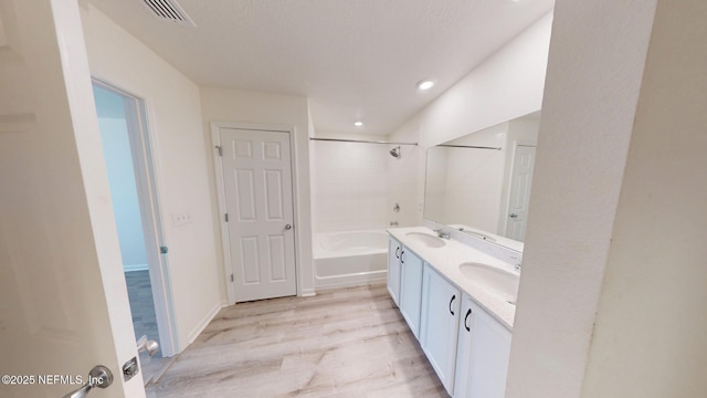 bathroom featuring double vanity, bathtub / shower combination, visible vents, a sink, and wood finished floors