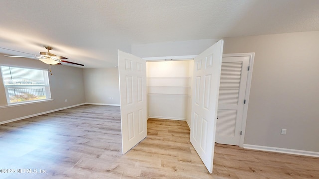 unfurnished bedroom featuring light wood finished floors, ceiling fan, baseboards, and a textured ceiling