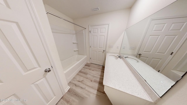 full bath featuring washtub / shower combination, visible vents, wood finished floors, and vanity