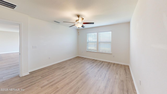 empty room featuring light wood finished floors, baseboards, visible vents, and a ceiling fan