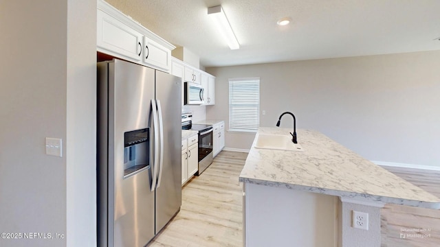 kitchen with appliances with stainless steel finishes, light wood-style floors, light countertops, and a sink