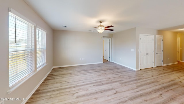 unfurnished room with ceiling fan, wood finished floors, visible vents, and baseboards