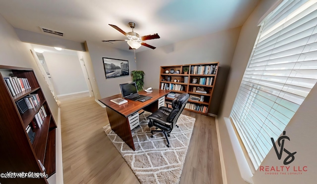 office featuring light wood-type flooring, visible vents, ceiling fan, and baseboards