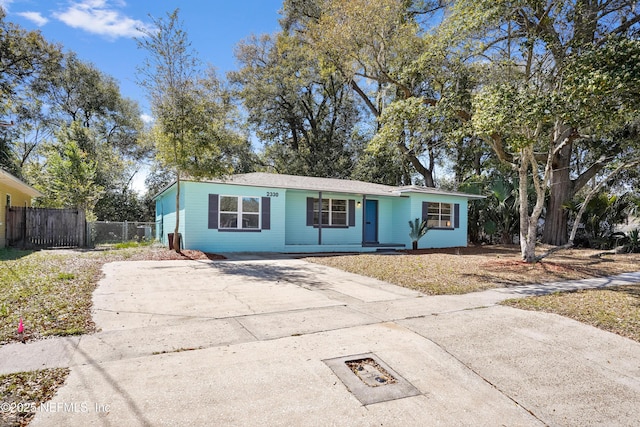 ranch-style house featuring concrete driveway and fence