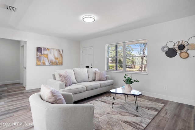 living room featuring baseboards, visible vents, and wood finished floors