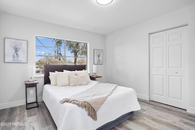 bedroom featuring a closet, baseboards, and wood finished floors