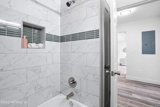 full bathroom featuring electric panel, baseboards, wood finished floors, bathtub / shower combination, and a textured ceiling