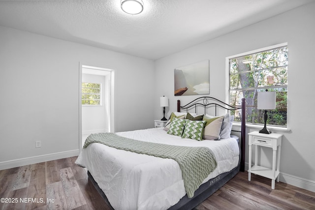 bedroom featuring a textured ceiling, baseboards, and wood finished floors