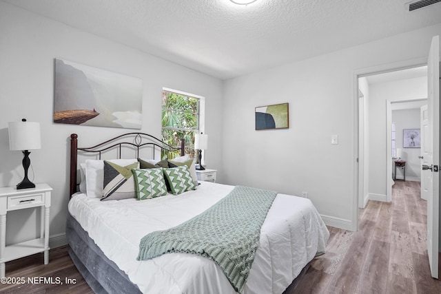 bedroom with baseboards, visible vents, and wood finished floors