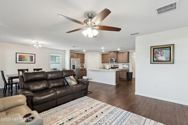 living area with dark wood-style floors, visible vents, ceiling fan, and baseboards