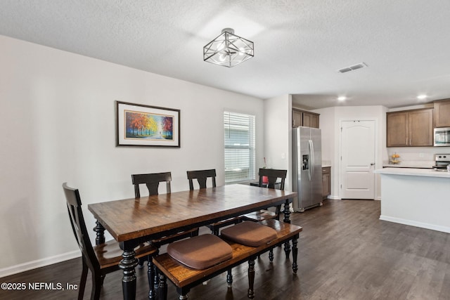 dining space featuring a textured ceiling, dark wood-type flooring, visible vents, and baseboards