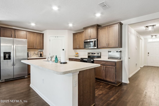 kitchen featuring visible vents, appliances with stainless steel finishes, dark wood-type flooring, light countertops, and a sink