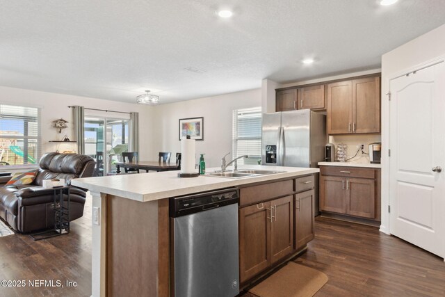 kitchen with stainless steel appliances, dark wood-type flooring, a sink, open floor plan, and light countertops