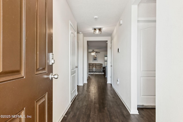 hall with baseboards and dark wood finished floors