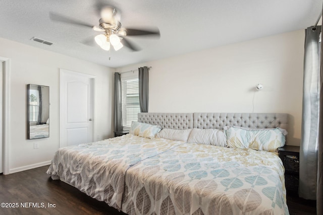 bedroom with ceiling fan, a textured ceiling, dark wood-style flooring, visible vents, and baseboards