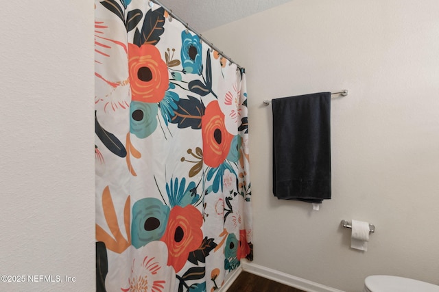 full bath with a shower with curtain, wood finished floors, toilet, and baseboards