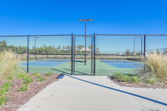 view of sport court with a gate and fence