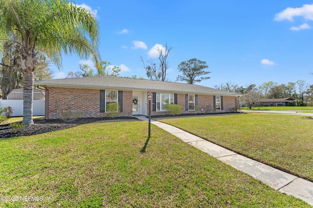 ranch-style home with brick siding, a front yard, and fence