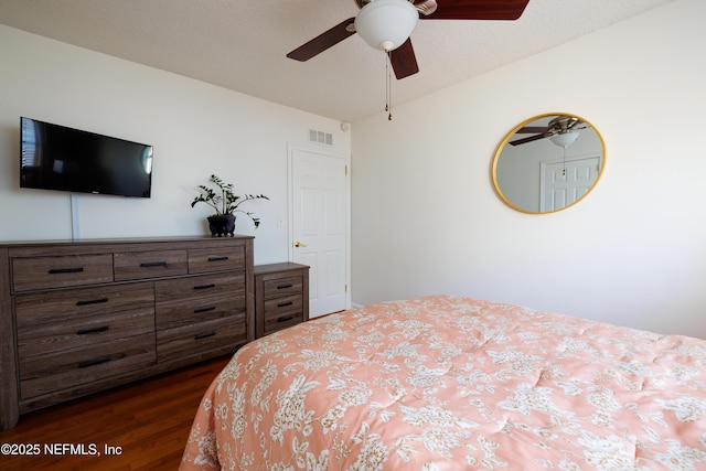 bedroom with ceiling fan, a textured ceiling, visible vents, and dark wood-type flooring