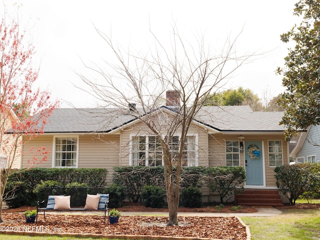 ranch-style home with a shingled roof and a chimney