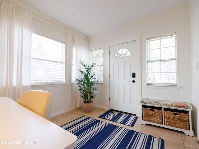 foyer entrance featuring light tile patterned floors, ornamental molding, and baseboards