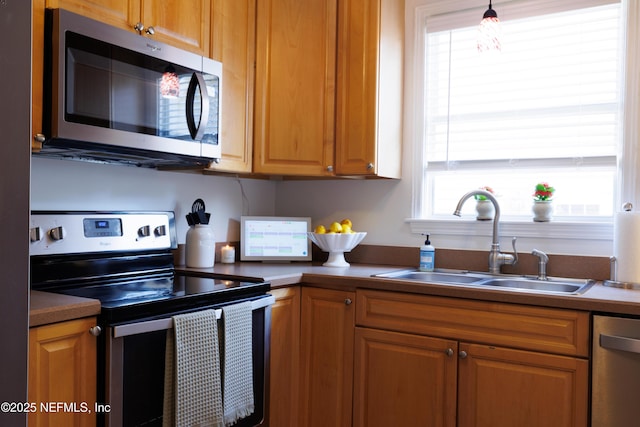 kitchen with appliances with stainless steel finishes, brown cabinetry, and a sink