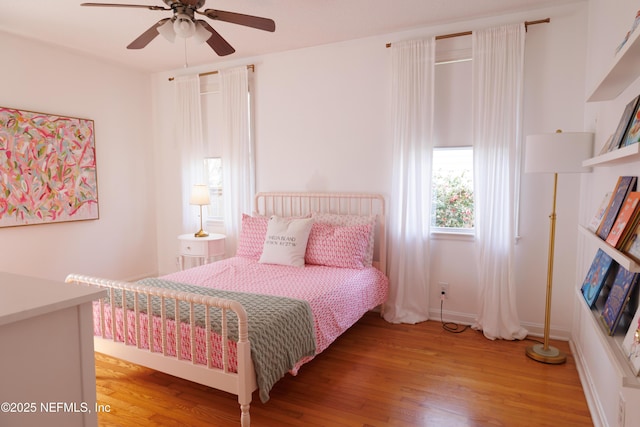 bedroom featuring a ceiling fan, light wood-style flooring, and baseboards