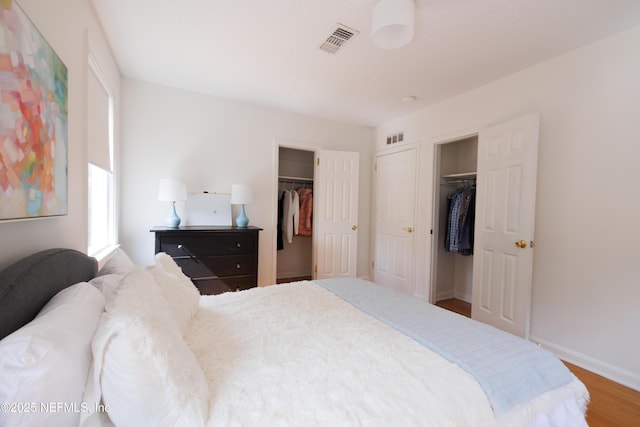 bedroom featuring visible vents, baseboards, and wood finished floors