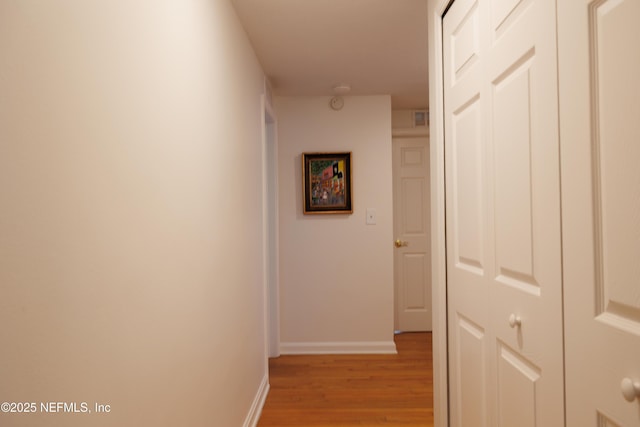 corridor featuring baseboards, visible vents, and light wood-style floors