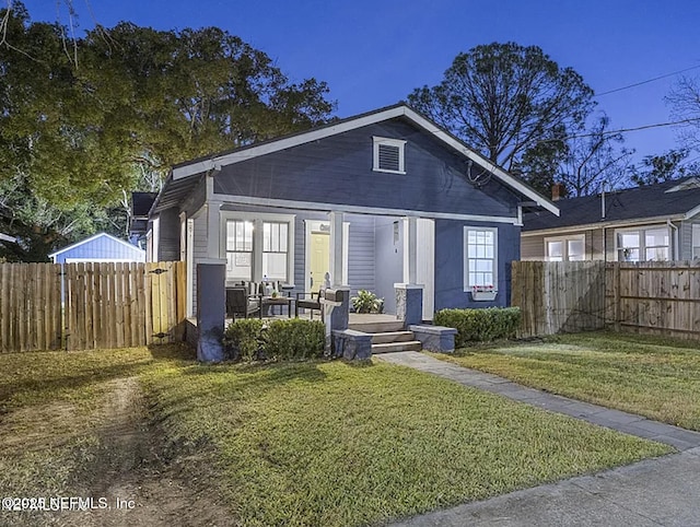 back of property with covered porch, fence, and a lawn