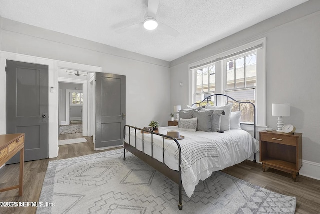 bedroom featuring a textured ceiling, ceiling fan, wood finished floors, and baseboards