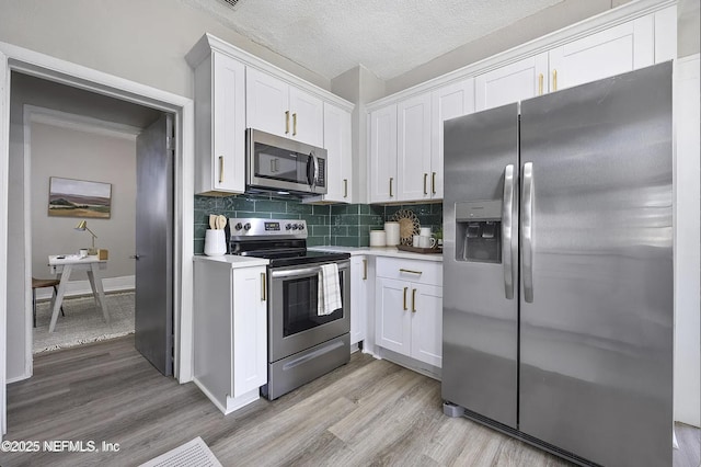 kitchen featuring stainless steel appliances, white cabinetry, light wood-style floors, light countertops, and backsplash