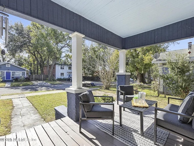 wooden terrace featuring a lawn, fence, and an outdoor living space