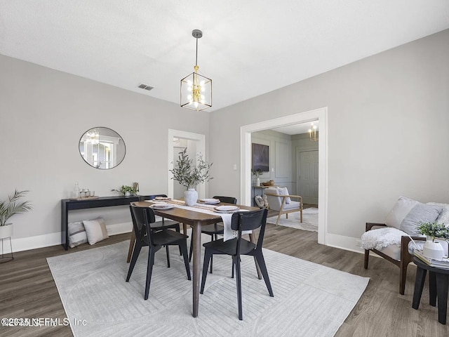 dining room with baseboards, visible vents, a chandelier, and wood finished floors