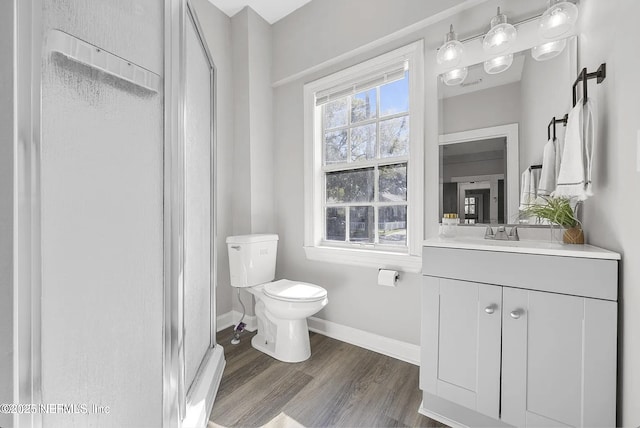 bathroom featuring baseboards, toilet, wood finished floors, vanity, and a shower stall