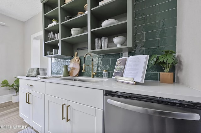 bar with light wood-style flooring, backsplash, a textured ceiling, stainless steel dishwasher, and a sink