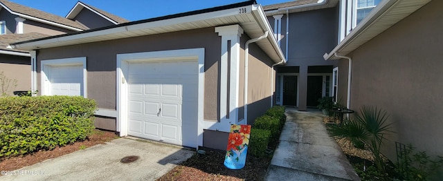 view of side of property featuring an attached garage and stucco siding