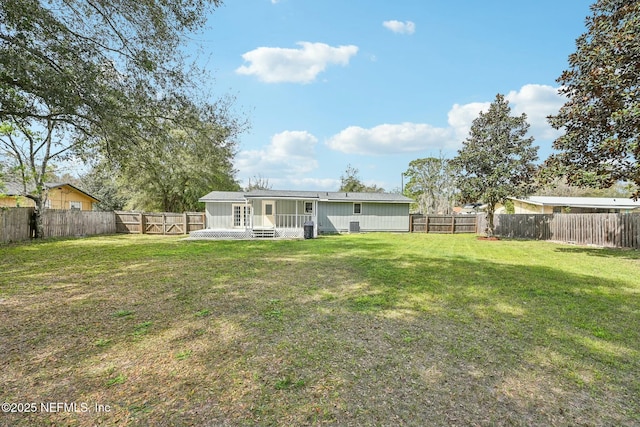 back of property with a fenced backyard and a yard