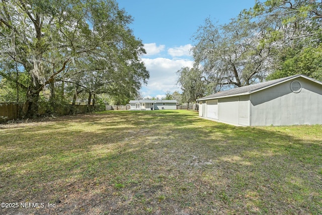 view of yard with a pole building, fence, and an outbuilding